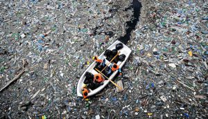 Photo of a small boat surrounded by floating plastics