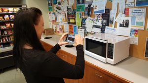Photo of a woman taking a photo of a microwave oven