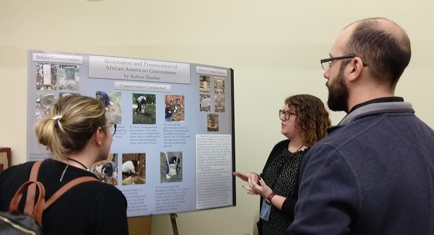 Attendees of the 2019 MAMA Conference interact with MSU Art & Design student Robyn Slusher as they view her poster presentation entitled Restoration and Preservation of African American Gravestones. 