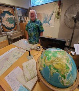 Photo of Jim Coombs surrounded by maps