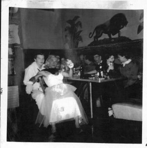 Group of young people in costume seated at a table with drinks. 