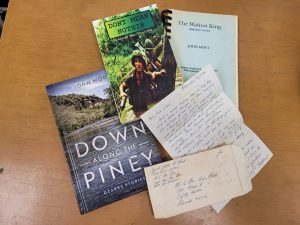 A selection of items from the John Mort collection on desk, including published books, along with hand written correspondence. 