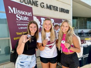 Students sport their buttons in front of Duane G. Meyer Library