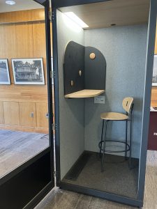 This is the inside of the phone booth on the third floor of the Duane G. Meyer Library. It has a stool, a small desk, a light, and a board with magnets.