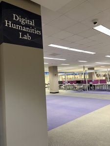 A computer lab in the basement of the Duane G. Meyer Library on Missouri State University campus. There are desks with computers in the background and a pillar with the words "Digital Humanities Lab" in the foreground