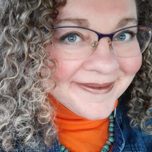 Woman with curly, brown hair and glasses