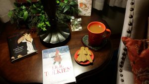 A table with books, gingerbread cookies, and a mug containing a warm, festive drink
