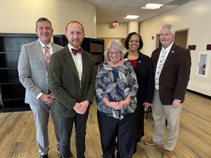 Three men and two women smile for a picture taken in the Ozarks Room. 